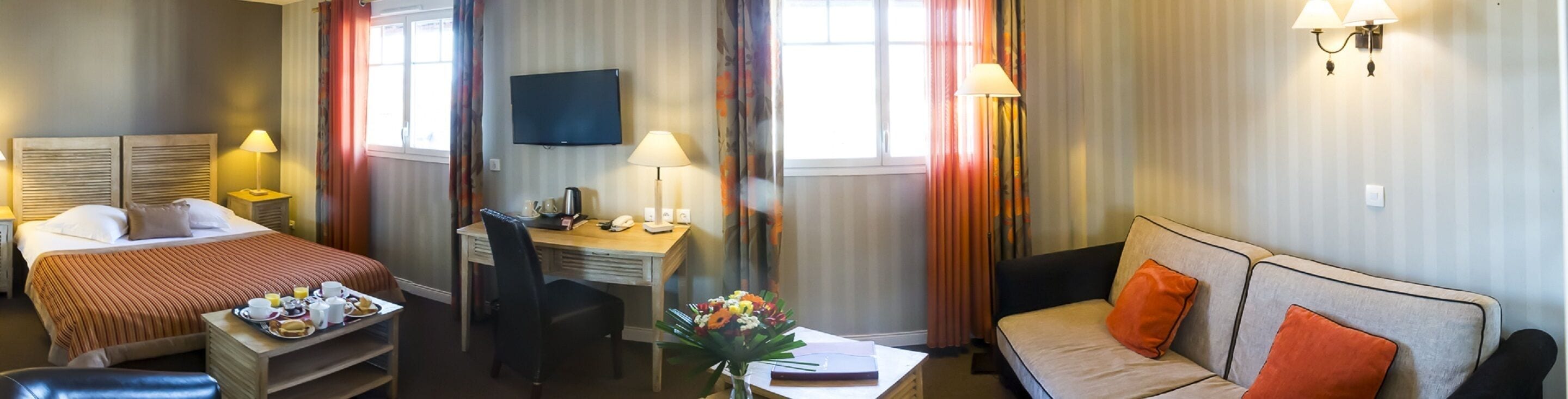 A hotel room with a bed, a desk, a sofa, and a television.