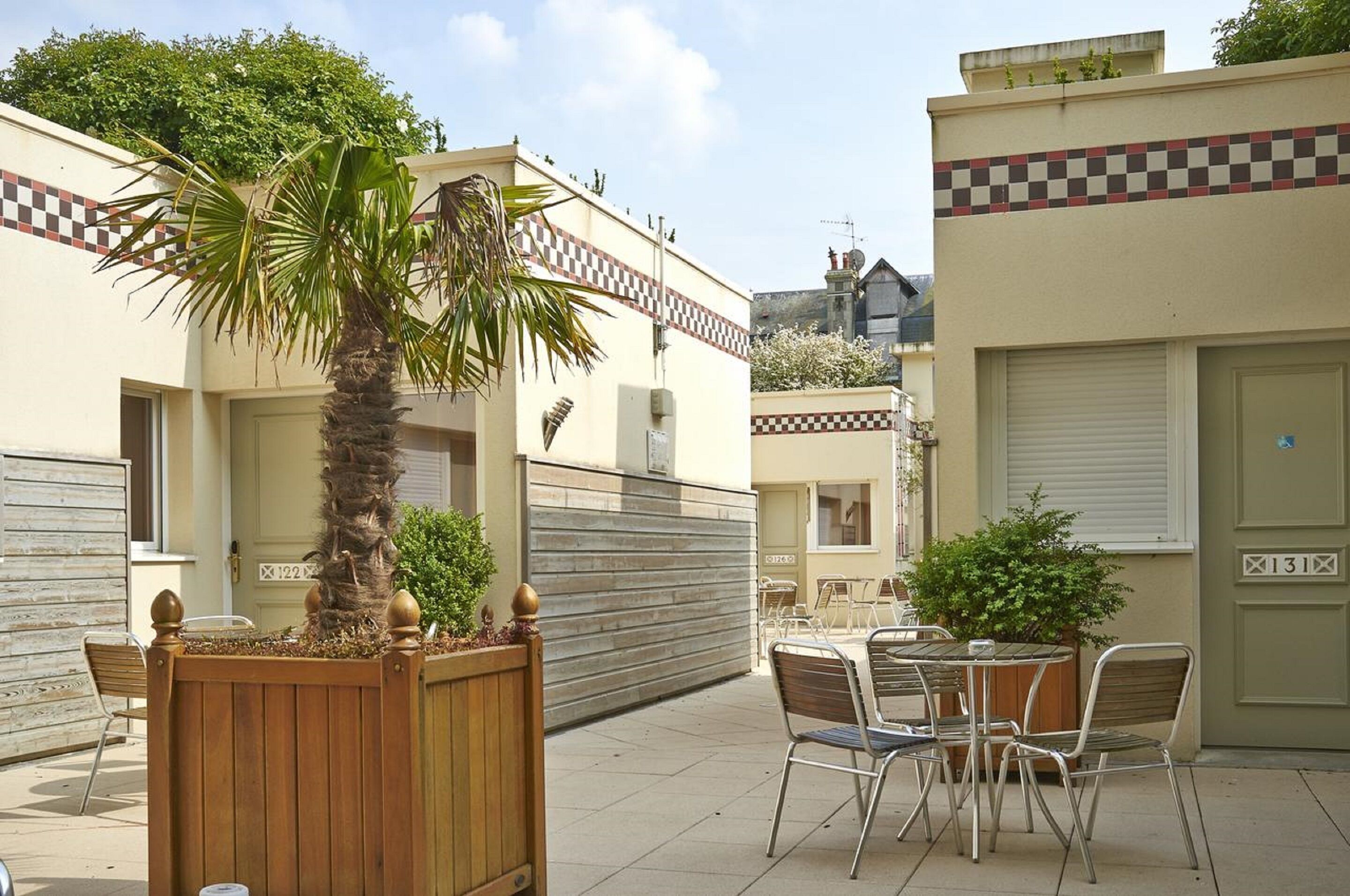A courtyard with a palm tree, a wooden fence, and a table with chairs.