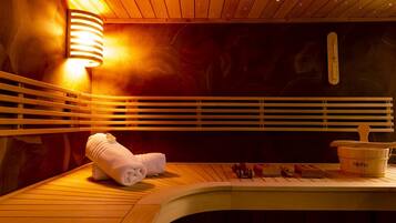 Experience relaxation in this serene sauna room, featuring a wooden bench, towel, and portable heater for a rejuvenating experience.