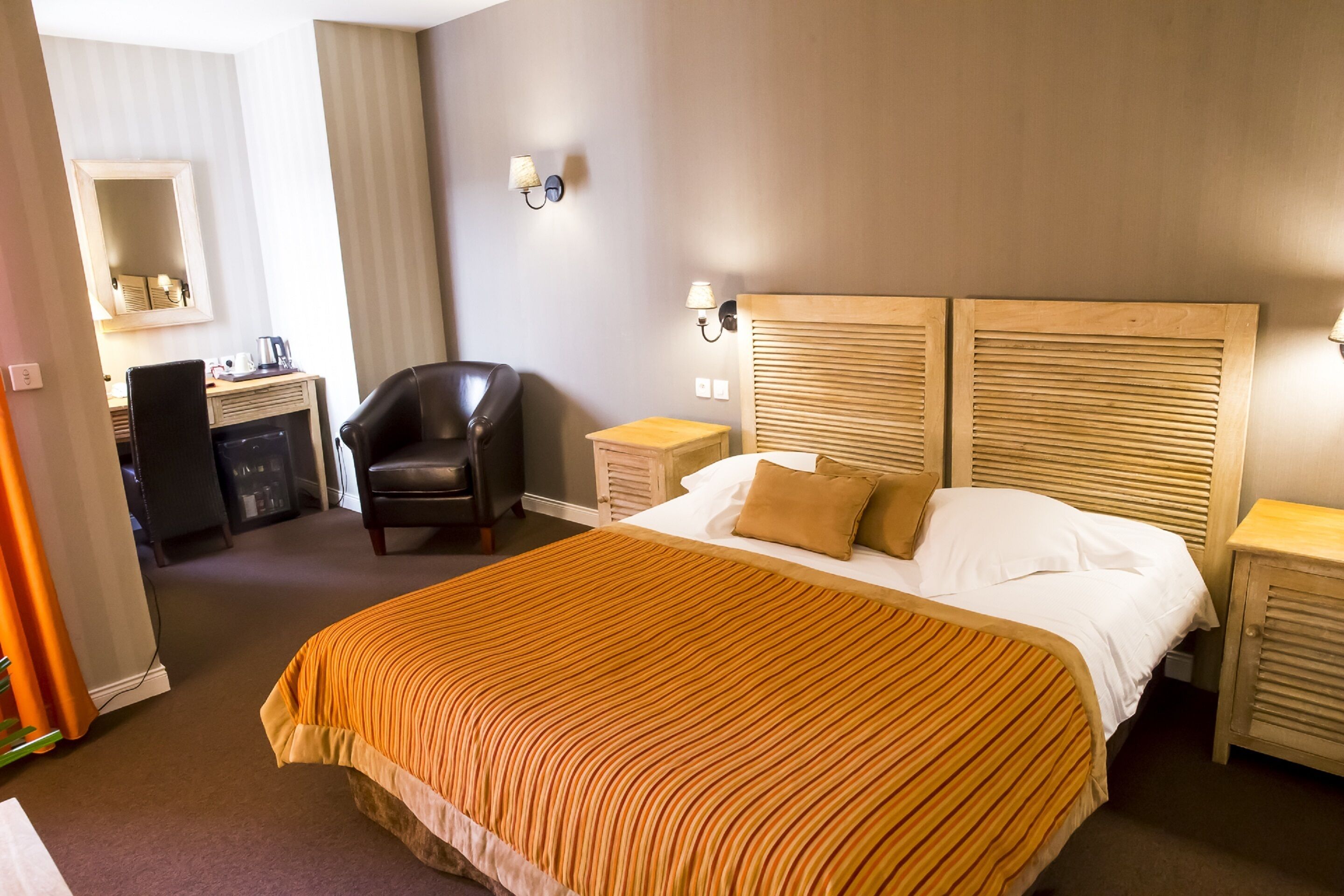Quarto de hotel com uma cama grande, uma escrivaninha, uma cadeira e um guarda-roupa.