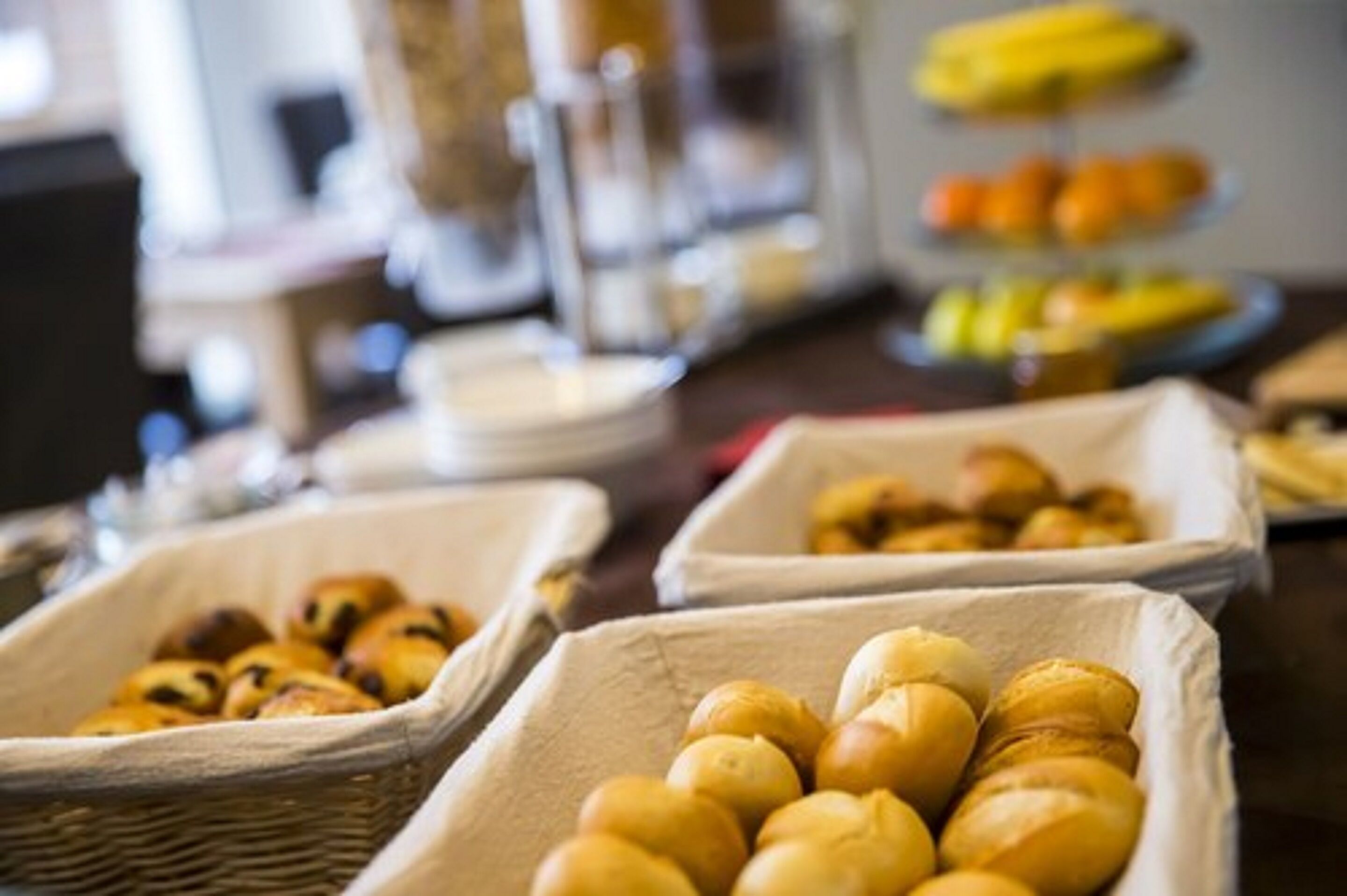 A buffet table with various food items, including baskets of pastries and a fruit display.