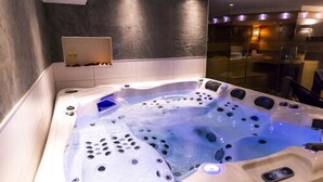 Un spa moderno con un amplio jacuzzi, cabina de ducha con mampara de vidrio y un diseño minimalista.