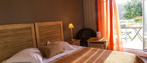 Un dormitorio con cama, mesita de noche, lámpara y vistas al patio exterior.