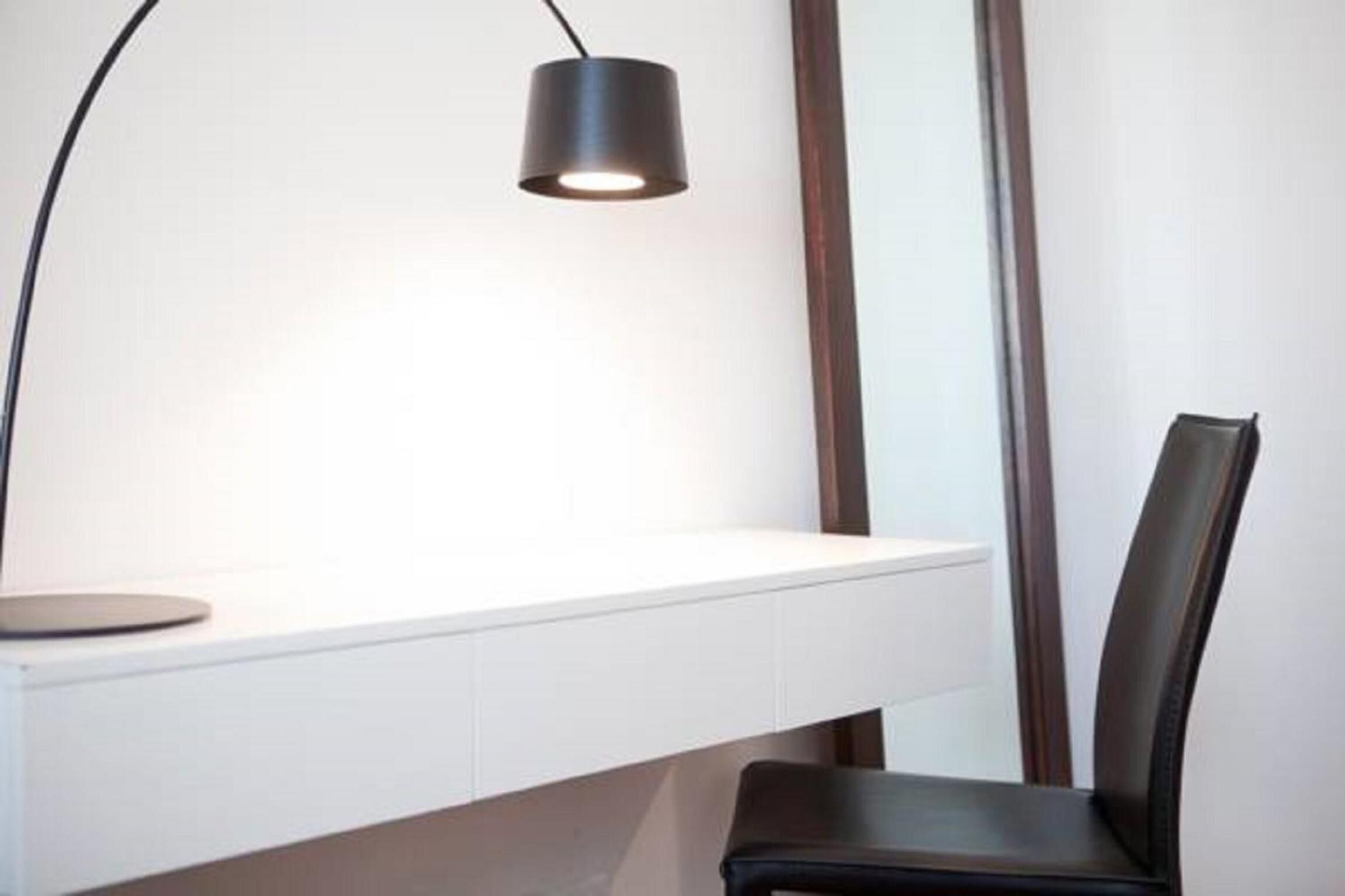A modern desk with a black lamp, a chair, and a white wall.