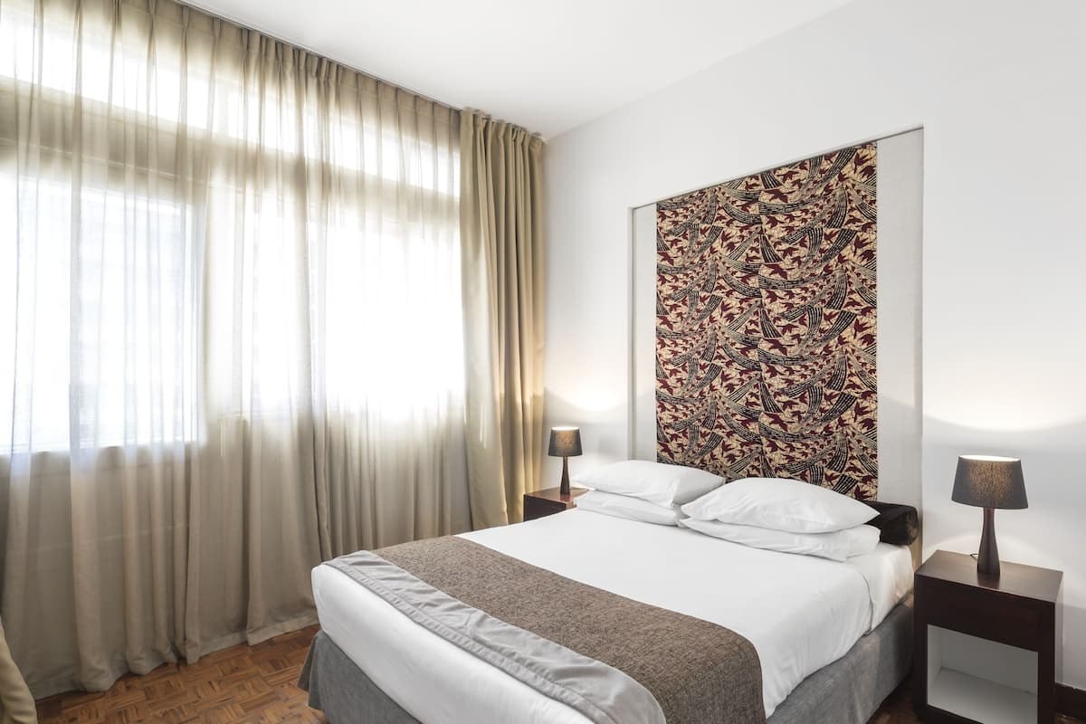 Une chambre moderne avec un grand lit, un plancher en bois et une décoration murale à motifs.