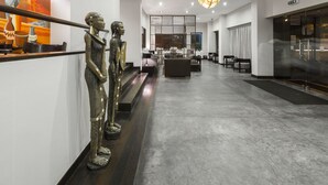 Un moderno vestíbulo de hotel con una escalera central, una recepción y un área de estar.