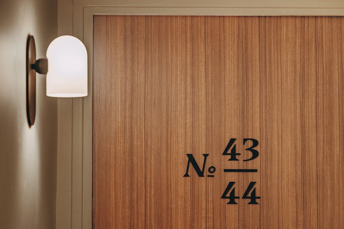 A wooden door with the number 43/44 and a wall-mounted light fixture.