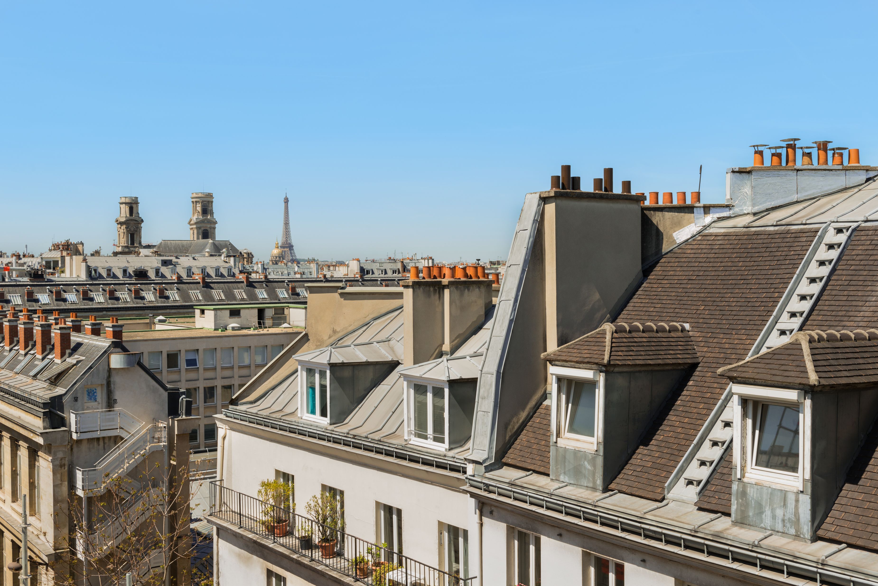 Een rij woongebouwen met schuine daken en meerdere schoorstenen, typerend voor Europese stadsarchitectuur.