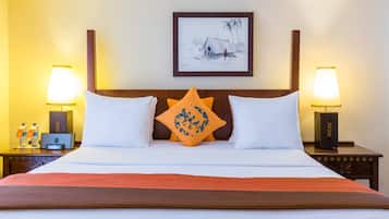 A hotel room with a bed, two bedside tables, a nightstand, a framed picture on the wall, and two lamps.
