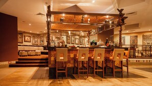 A bar area with a high counter, multiple stools, and a decorative ceiling.