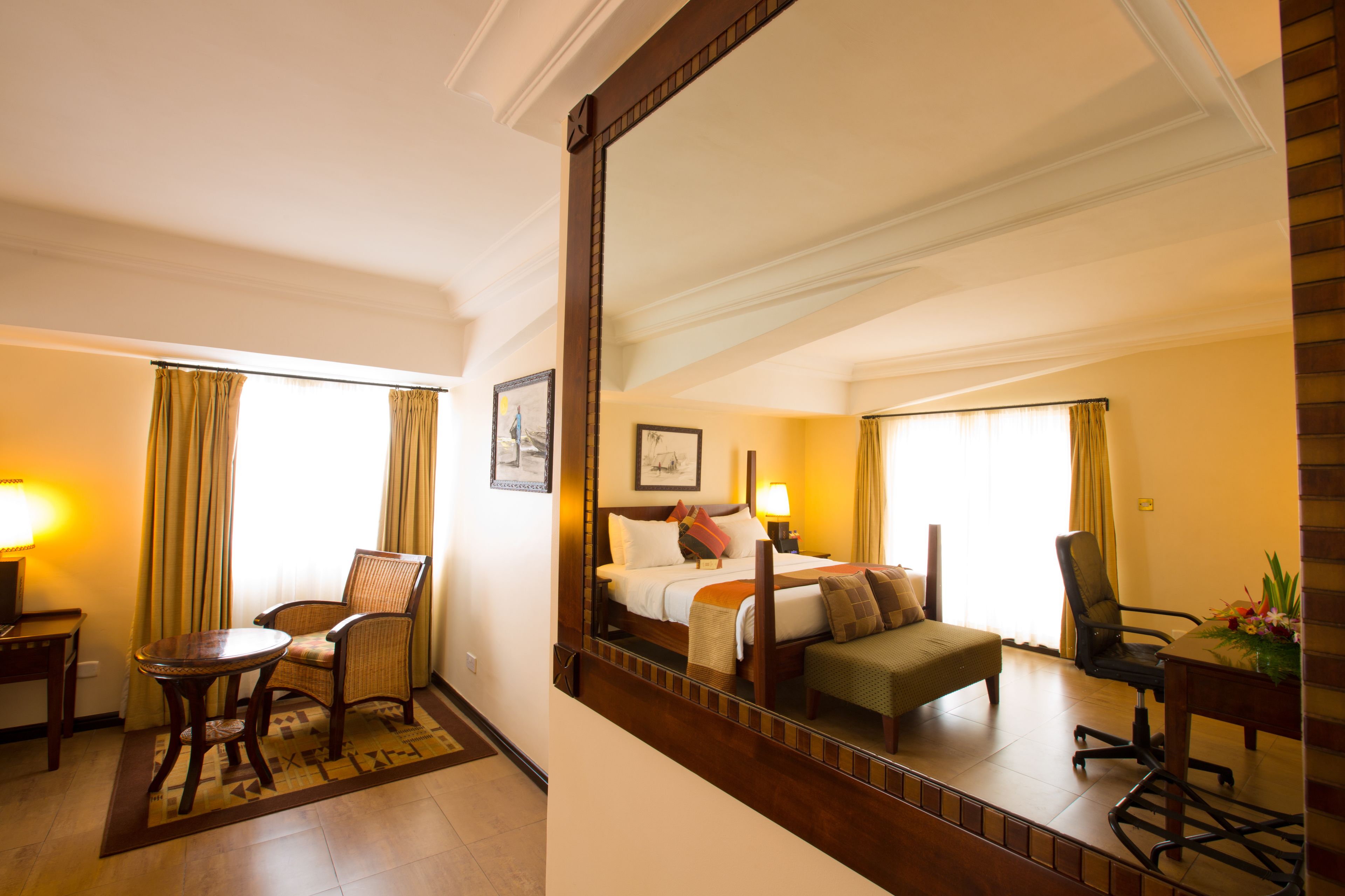 A hotel room with a bed, a chair, a small table, and a mirror.
