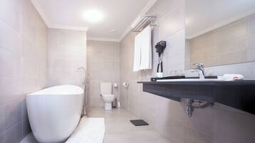 A modern bathroom with a freestanding bathtub, a toilet, and a sink with a towel rack.