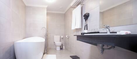 Un baño moderno con una bañera independiente, un inodoro y un lavabo con un perchero para toallas.