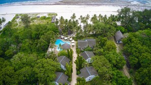 An aerial view of a resort with a swimming pool, palm trees, and beach access. - Pinewood Beach Resort and Spa (Diani Beach)