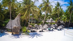 A beach resort with thatched-roof huts, palm trees, and a pool area. - Pinewood Beach Resort and Spa (Diani Beach)