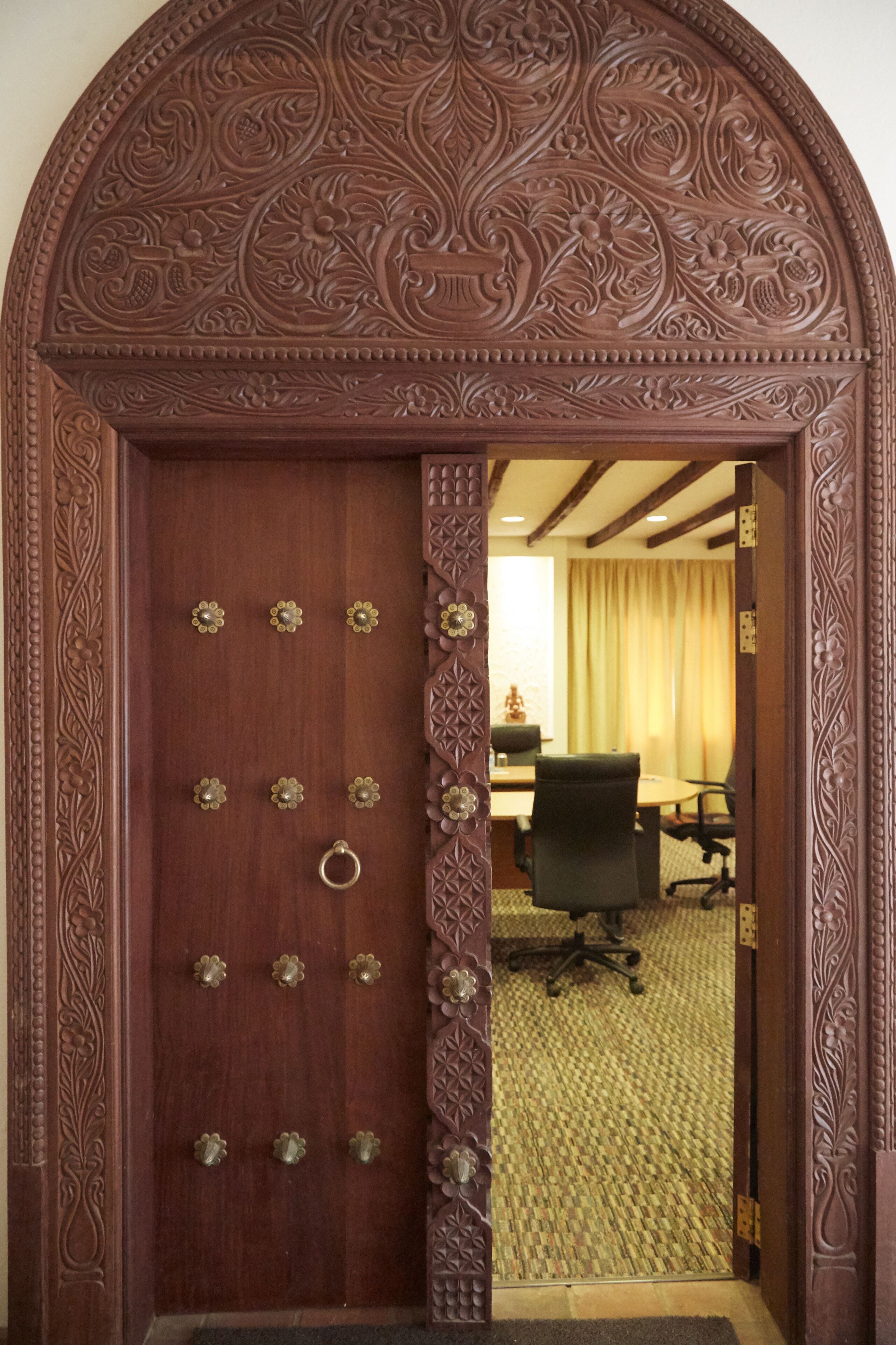 A wooden door with intricate carvings and a circular handle.