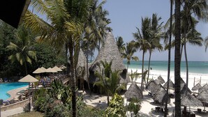 A resort with a pool, beach, and thatched-roof huts. - Pinewood Beach Resort and Spa (Diani Beach)