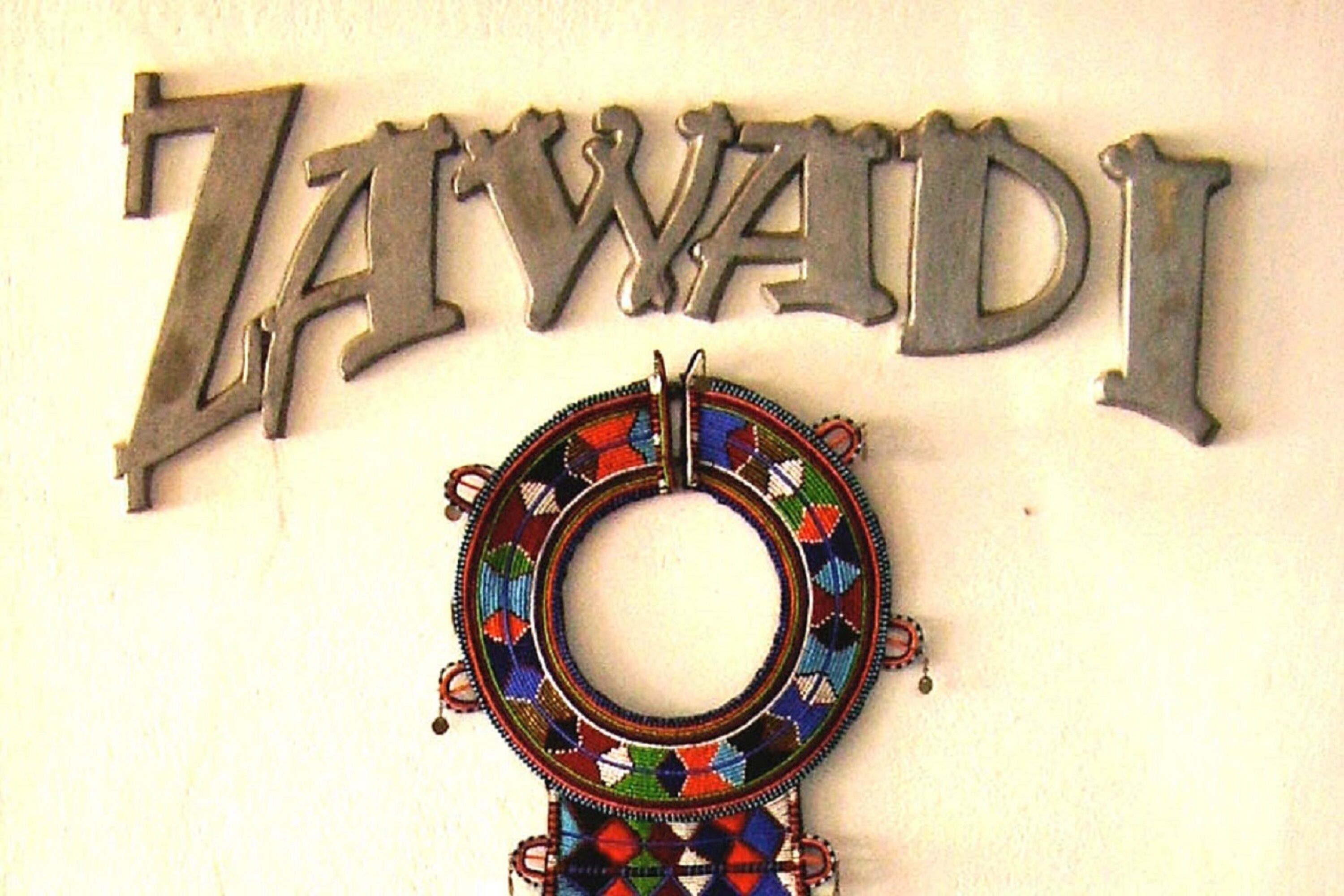 Un cartello decorativo con il nome 'ZAWADI' e un ornamento circolare colorato sottostante.