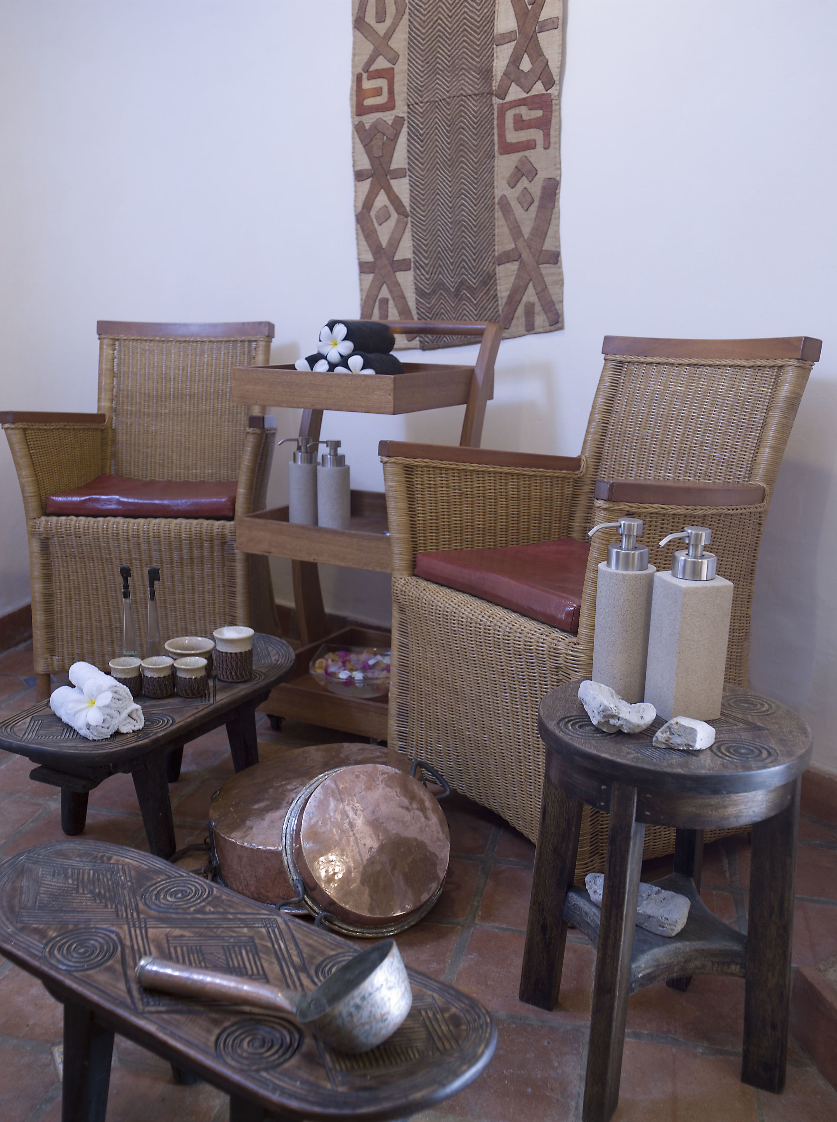 Una habitación con muebles de mimbre, una mesa de madera con un cuenco y un adorno colgante en la pared.