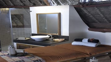 Experience a traditional retreat with a thatched roof, a large bed, and a cozy atmosphere.