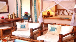 A room with two wooden beds, one with a canopy, and two wooden chairs. There is a table with decorative items and a vase with flowers. - Pinewood Beach Resort and Spa (Diani Beach)
