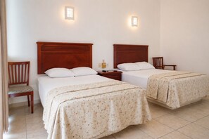 Habitación de hotel con dos camas, una silla, una mesita de noche y luces instaladas en la pared.