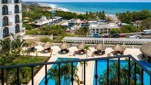 Un resort con piscina, vista al mar y sombrillas de techo de paja.