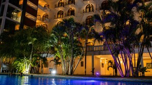 Un hotel con varios balcones, piscina y exuberante vegetación tropical.