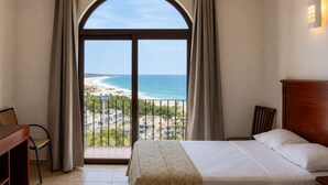 Una habitación de hotel con una cama, un escritorio y vistas a la playa.