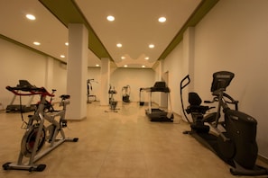 A gym with various exercise equipment including treadmills, stationary bikes, and elliptical machines.