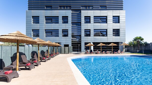 A modern building with a swimming pool, sun loungers, and umbrellas. - Hotel Nuevo Boston (Madrid)