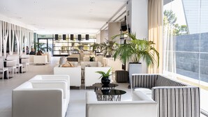 A modern hotel lobby with white sofas, a black coffee table, and large windows offering a view of the outdoors. - Hotel Nuevo Boston (Madrid)