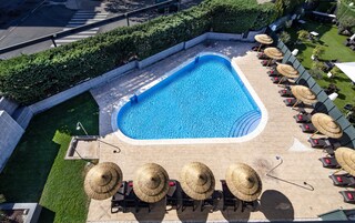 Una piscina al aire libre de temporada, sombrillas