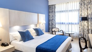 A hotel room with a large bed, bedside tables, a desk, and a chair. - Hotel Nuevo Boston (Madrid)