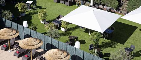 An outdoor seating area with lounge chairs, umbrellas, and tables.