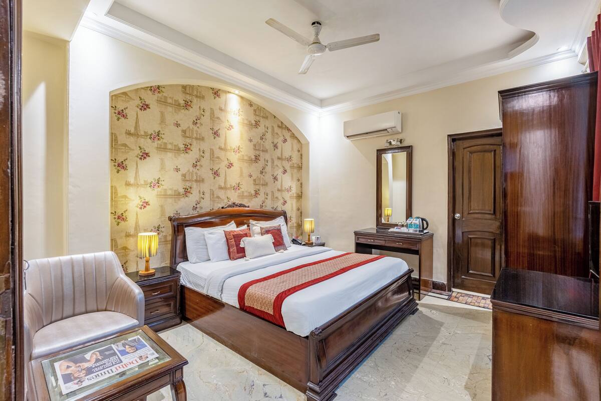 Un dormitorio con una cama grande, una mesita de noche de madera, una silla, un armario de madera y un ventilador de techo.