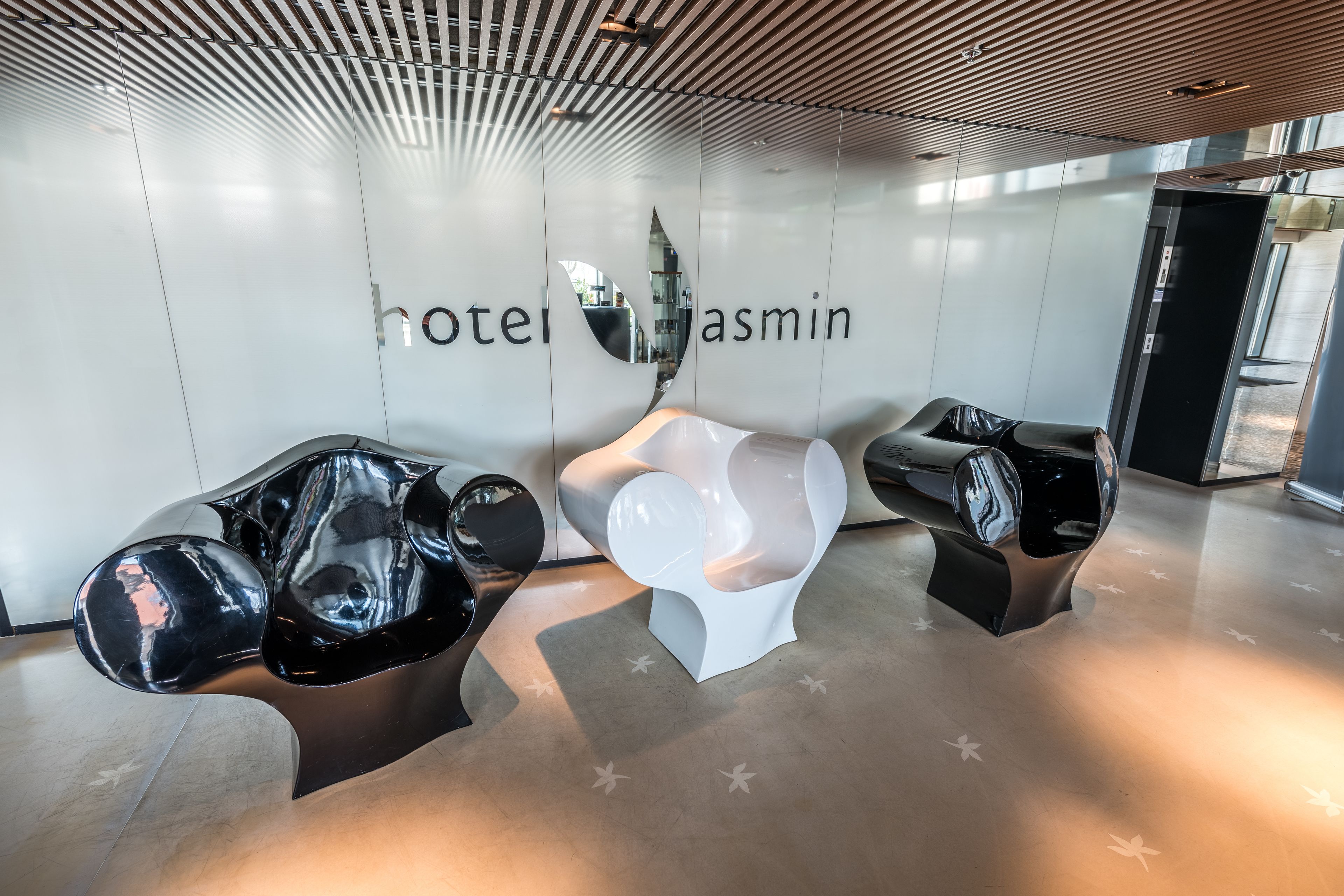 Un vestíbulo de hotel moderno con un diseño minimalista, que cuenta con una recepción y una zona de estar.