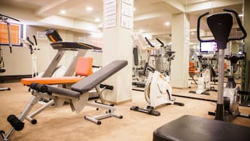 A gym with various exercise equipment, including treadmills, stationary bikes, and weight machines.