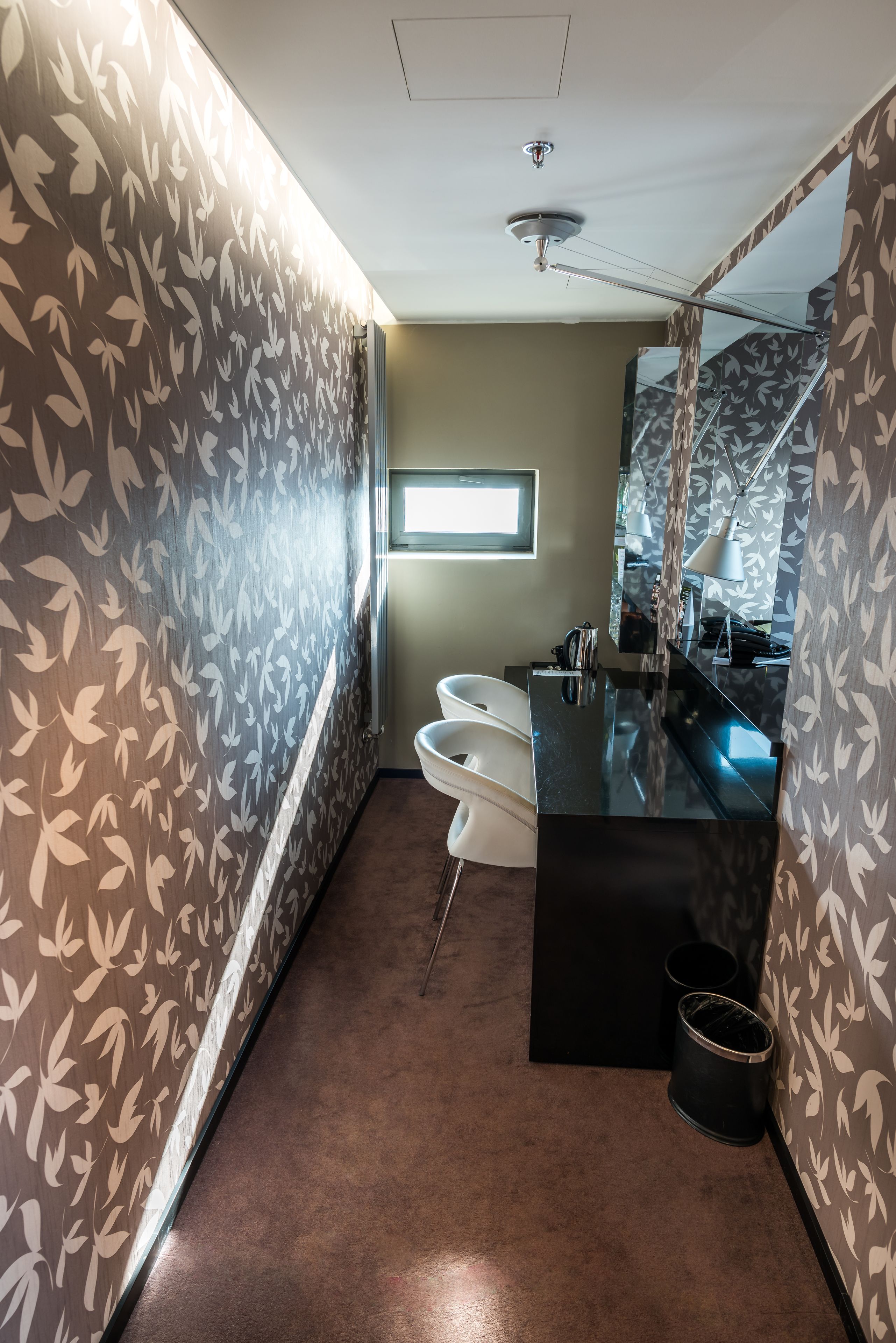 A bathroom with a modern design, featuring a black sink, white toilet, and a mirror with a leaf pattern.