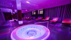 A spa area with a central hot tub, multiple lounge chairs, and a modern interior design. - Hotel Yasmin (Kosice)