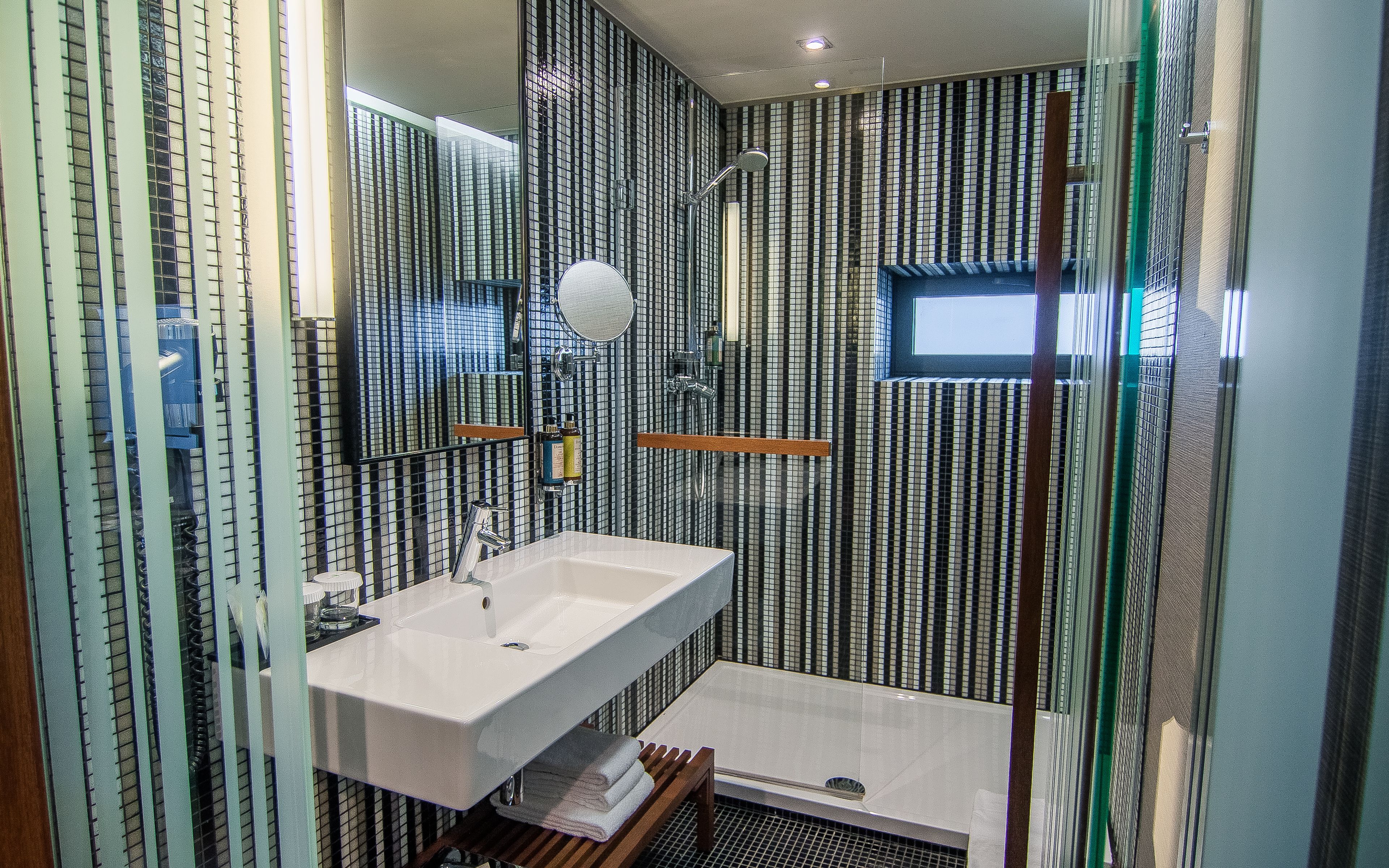 A modern bathroom with a large mirror, a white sink, and a shower area.