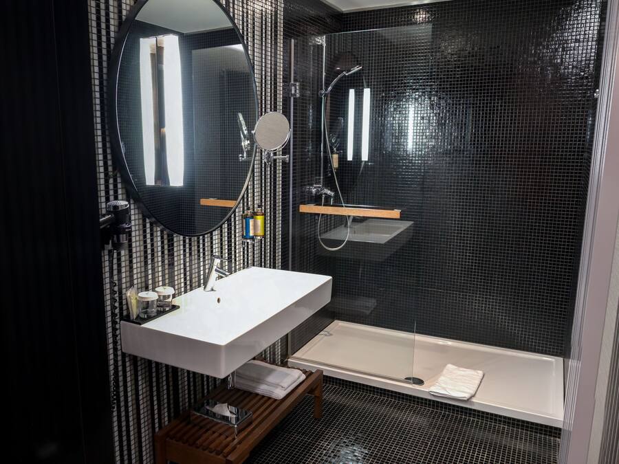 Ein modernes Badezimmer mit großem Spiegel, weißem Waschbecken und einer Badewanne.