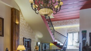 A spacious interior with a staircase, a chandelier, and a patterned wall. - Grecian Castle Hotel (Chios)