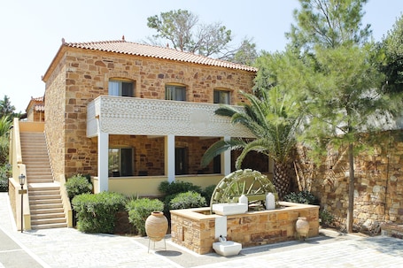 A stone building with a tiled roof, a staircase, and a water wheel.