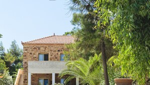 A stone building with a tiled roof, a staircase, and large terracotta pots. - Grecian Castle Hotel (Chios)