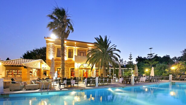 A poolside area with lounge chairs and umbrellas, a bar, and a building with a pool. - Grecian Castle Hotel (Chios)
