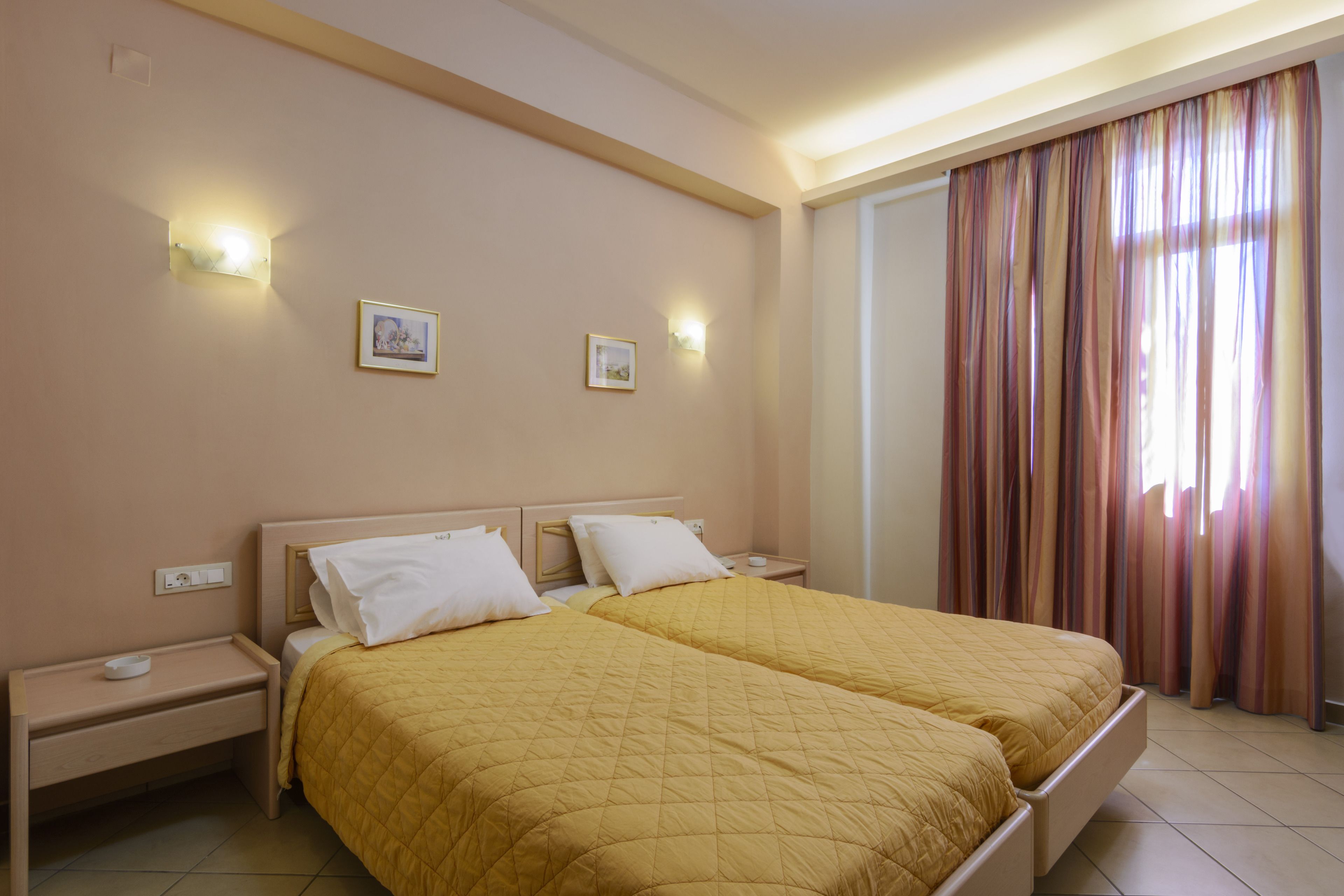A double bed with a yellow quilt, two bedside tables, and wall-mounted lights.