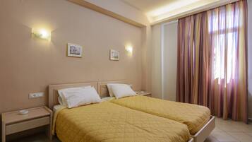 A double bed with a yellow quilt, two bedside tables, and wall-mounted lights.