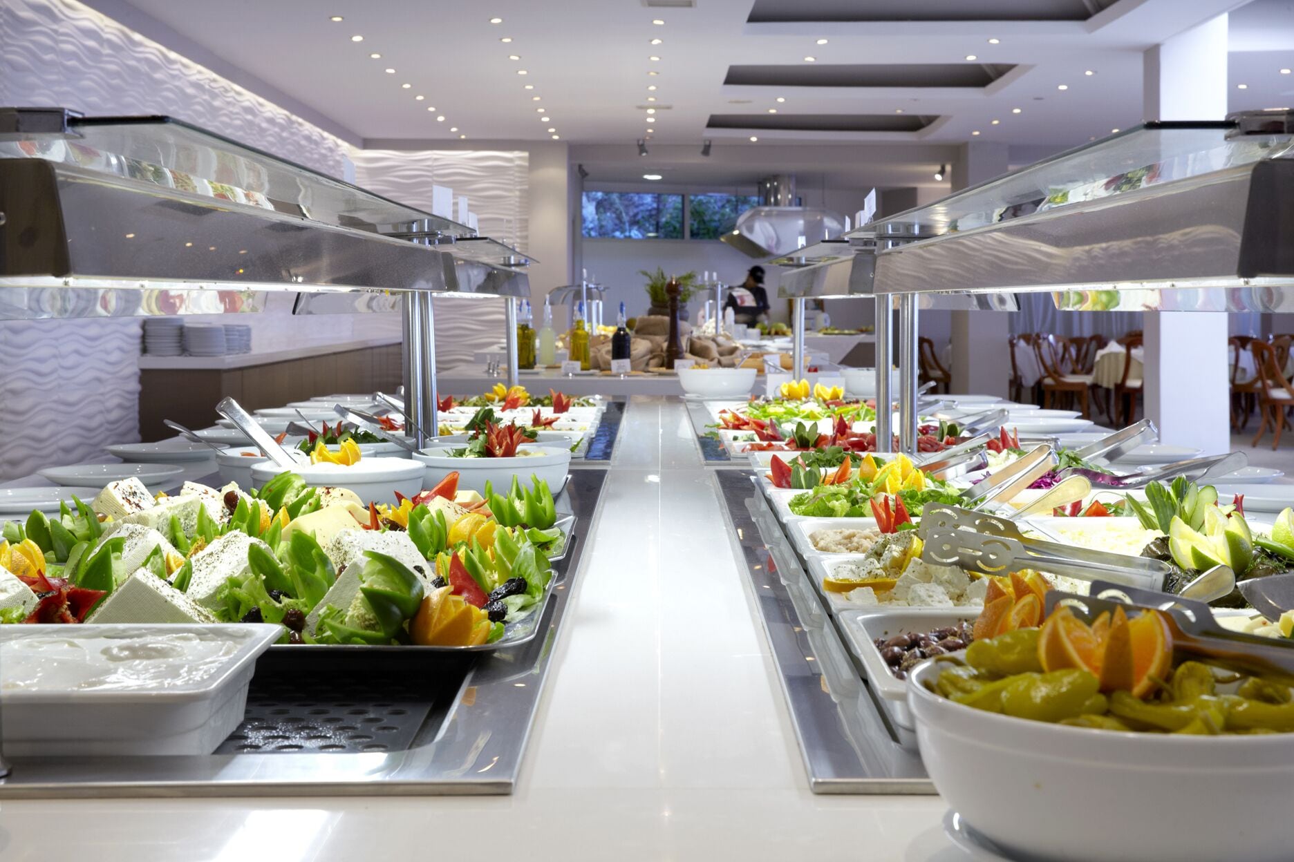Un bufé con diversas opciones de comida y utensilios de servicio.