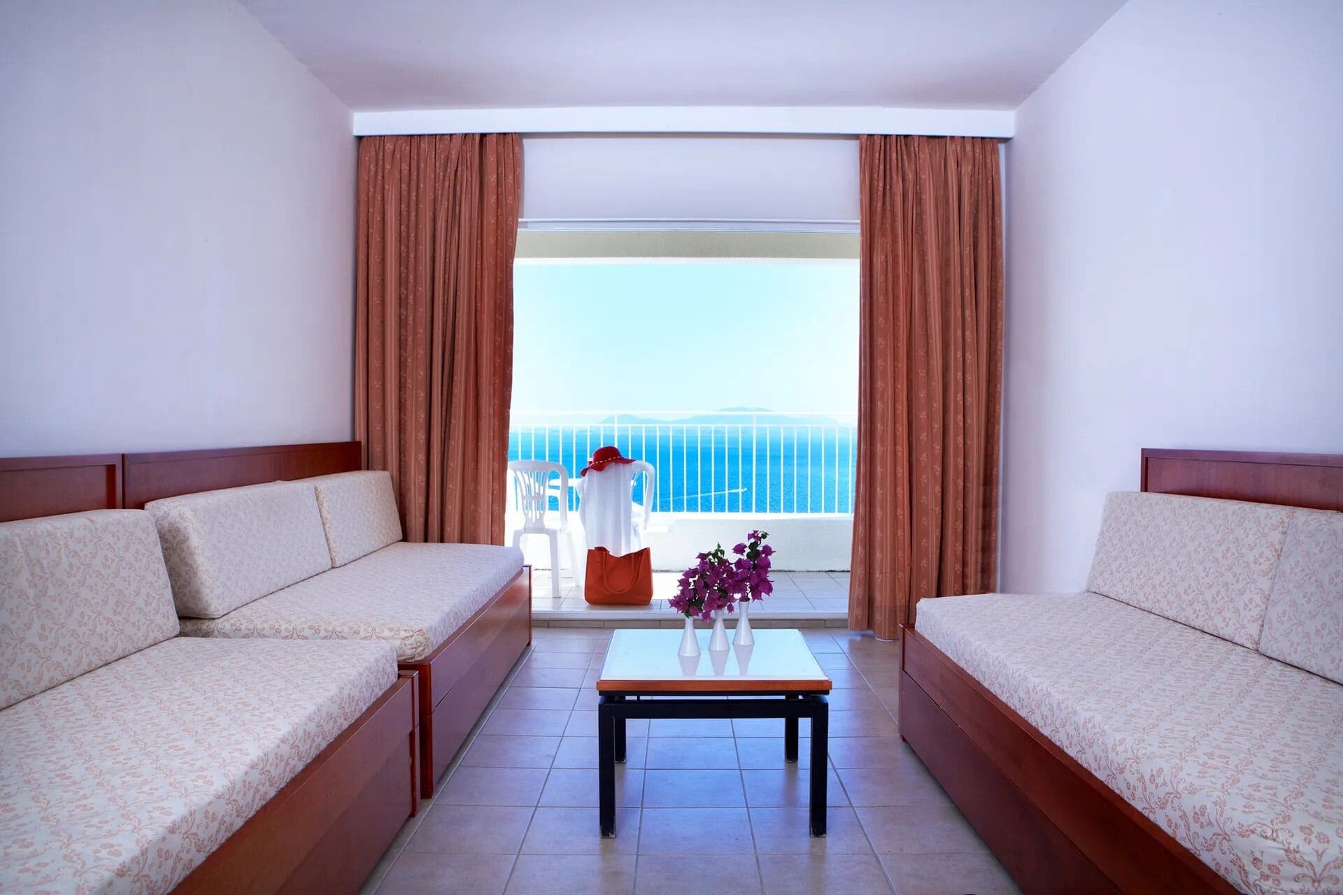 Habitació d'hotel amb dos sofàs orientats cap a un balcó amb vista al mar.